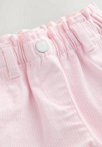 Gros plan sur un pantalon à taille élastique rayé rose et blanc, avec passants pour ceinture, poche avant et fermeture par bouton argenté.