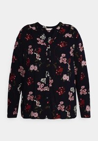 Svart långärmad skjorta med knappar, prydd med röda, rosa och vita blommönster samt gröna blad, liggande platt på en vit yta.