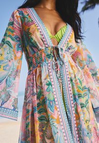 Floral print cover-up with bell sleeves, featuring a smocked waist, plunging neckline, and vibrant colors of pink, green, and blue.