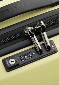 Valigia rigida gialla con una cerniera nera, doppie serrature, un foro per la chiave e un pannello per lucchetto a combinazione con quadranti numerici.