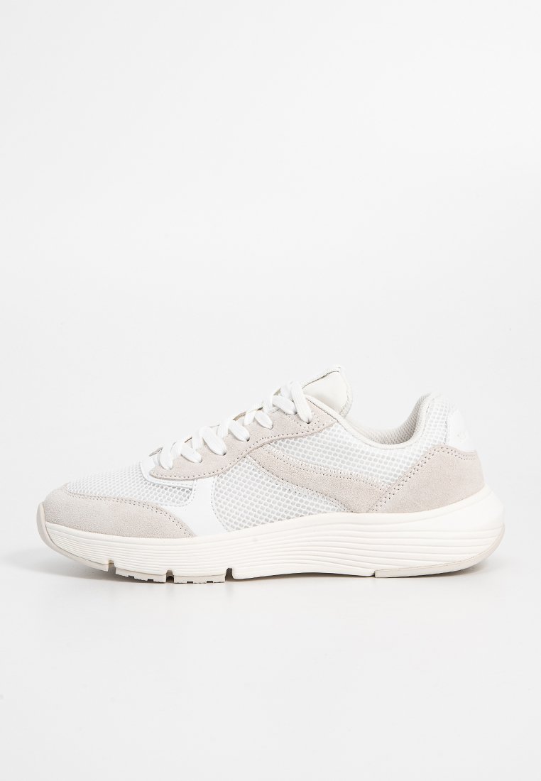 Graue und weiße Sportschuhe mit einem Obermaterial aus Mesh, Suede-Akzenten und einer strukturierten Gummisohle in runder Form. Schnürverschluss.