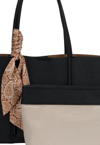 Czarna torebka tote z teksturowanej skóry z dwoma uchwytami, z kremową dolną częścią i brązowym szalem w paisley związanym na uchwycie.