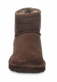 Bottines en suède marron avec doublure douce, semelle en caoutchouc plate, bout rond et un design simple avec des coutures. Pas de matériel ou de motifs visibles.