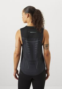 Svart trenings tanktopp med mesh-back og refleksdetaljer samt ergonomisk design. Inkluderer en subtil logo ved halsen.