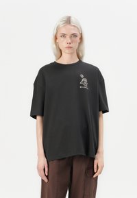 Black oversized t-shirt made of cotton, featuring a front graphic with a lion head and sun, short sleeves, and a round neckline.