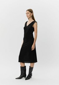 Must kleit pitsilise äärega, varrukateta, kitsas lõige, poolpikkus, sobitatud põlveni ulatuvate tekstuursete mehiste saapadega.