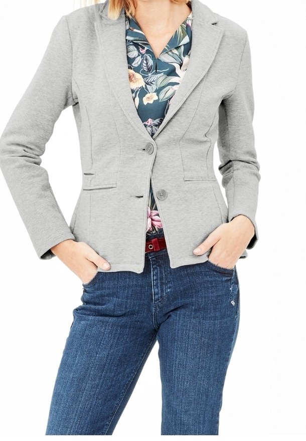 Blazer grigio con finitura testurizzata, caratterizzato da una chiusura a bottone singolo e due tasche frontali, indossato su una camicia floreale e abbinato a jeans blu.