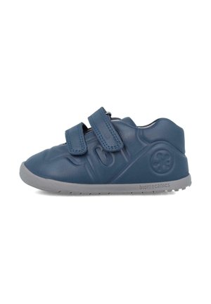 Zapato azul de cuero con dos correas de velcro, punta redonda y suela de goma gris con un patrón texturizado y logo de la marca.