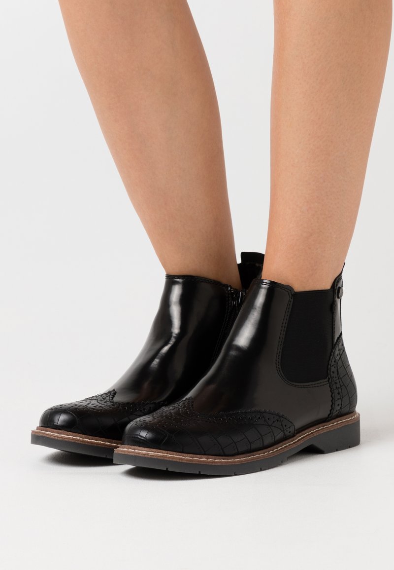 Black leather ankle boots with elastic side panels, textured crocodile pattern on the toe, and brown stitching around the sole.