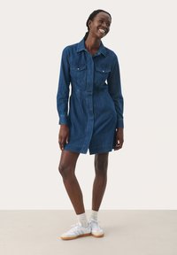 Denim dress with a collar, long sleeves, and two chest pockets. Dark blue color, knee-length, featuring a straight cut and button front detail.
