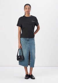 Svart kortärmad t-shirt, blå denimmaxikjol med frontslits, svart handväska och svarta loafers. Enkel design, avslappnad klädsel.