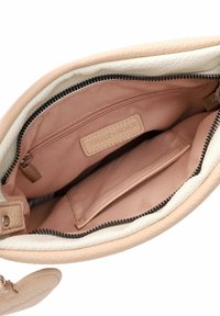 Light pink leather handbag interior with a tan fabric lining, zippered pocket, and a smooth texture. Features a branded label.