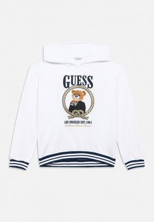 Witte capuchontrui met marineblauwe strepen op de manchetten en zoom, met een teddybeer binnen een touwen cirkel en tekst "GUESS Los Angeles Est. 1981".