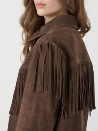 Veste en daim marron avec de longues franges sur les épaules, détail de col et texture lisse. Présentée dans un design ajusté sans fermetures visibles.