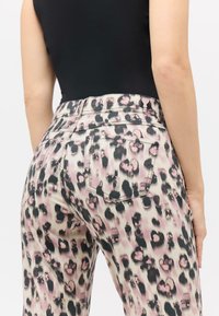 Traperice s leopard uzorkom u nijansama ružičaste i crne boje, glatke teksture, visokog struka i stražnjim džepovima.
