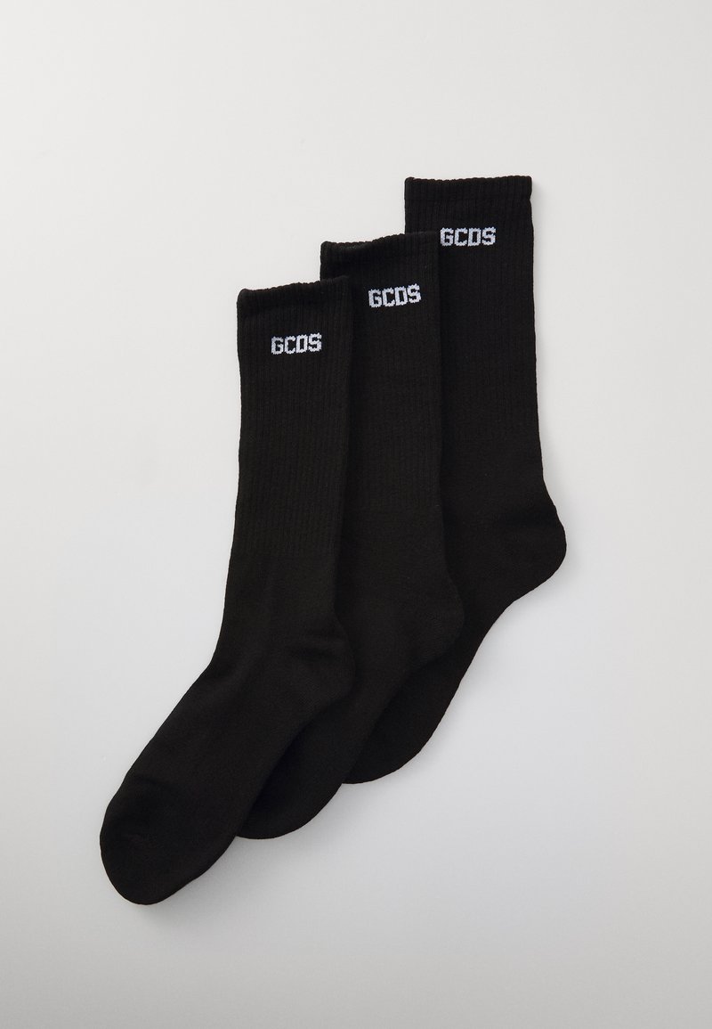Calze nere con design a coste, con il logo bianco "GCDS" in cima. Tre paia esposti, mostrando colore e texture costanti.