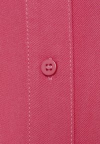 Pink fabric with a fine texture, featuring a button detail and visible stitching along the edge. The button is round and slightly glossy.