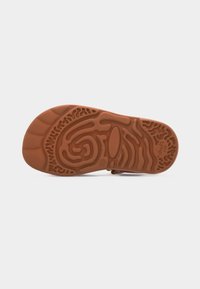 Καφέ λαστιχένια σόλα παιδικού παπουτσιού που φαίνεται από κάτω, με ανάγλυφο κυματιστό σχέδιο πέλματος για καλύτερη πρόσφυση.