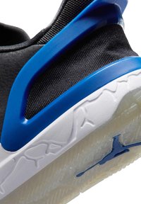 Zwart-blauwe sportschoen met witte zool, met een reliëfpatroon en een blauw logo op de doorschijnende buitenzool.