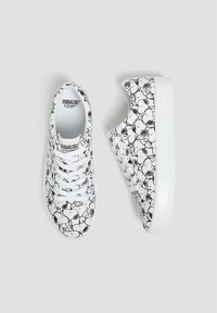 Baskets blanches à lacets avec motif de personnage Snoopy en noir et blanc des Peanuts, vues de dessus et de côté sur un fond gris.