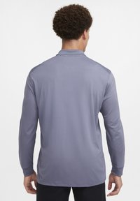 Long-sleeve, gray athletic shirt in smooth fabric, featuring a simple collar and no visible logos or patterns. Back view shows a classic fit.