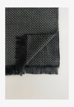 Graue Decke im Fischgrätenmuster mit fransenbesetzten Kanten, aus weichem Material gefertigt, in abwechselndem Schwarz und hellgrau.