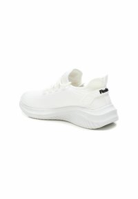Zapatilla deportiva blanca con parte superior de punto texturizado, cordones elásticos y suela blanca acolchada. Presenta un acento de logo negro en el talón.