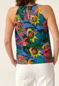 Top senza maniche con stampa floreale, caratterizzato da uno sfondo blu, fiori multicolori e una apertura a forma di chiave sul retro. Tessuto leggero.