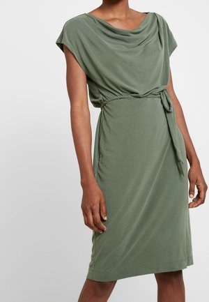 Zielona sukienka do kolan wykonana z miękkiego materiału, z marszczonym dekoltem, krótkimi rękawami typu kapturek i przewiązanym akcentem w talii. Jednolity kolor o gładkiej fakturze.