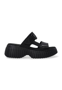Zwarte sandalen met een dikke, ribbelige zool en een gladde bovenkant. Beschikt over brede banden en een zijgesp voor aanpassing. Zachte, gestructureerde afwerking.