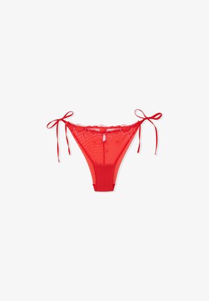 String rouge en mesh transparent avec une ceinture rouge unie. Présente des motifs de cœurs le long du haut et des nœuds décoratifs sur les côtés.