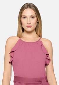 Gerafftes Neckholder-Oberteil in gedämpftem Rosa. Weicher, leichter Stoff mit tailliertem Schnitt und passendem Gürtel. Weiche Drapierungen sorgen für Struktur.