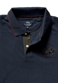 Tmavě modrá polokošile s vínovým límečkem, zapínáním na tři knoflíky a vyšívaným motivem jezdců. Bavlněná látka s texturovaným povrchem.