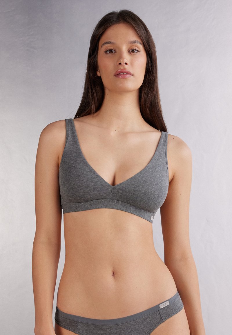 Grå bomullsbralette med djup V-ringning, breda axelband och sömlös design. Har en åtsittande band och mjukt, texturerat tyg.
