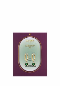 Gouden creolen met smaragdgroene zirconia-gemstones, tentoongesteld op een merkkaart met een paarse achtergrond en lichtgroene accenten.