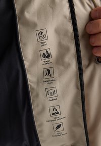 Giacca reversibile con proprietà antivento e idrorepellenti, dotata di cappuccio rimovibile, imbottitura isolante e materiali ecologici.