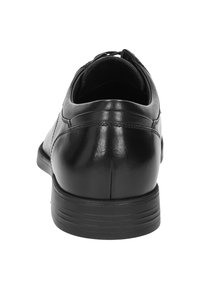 Scarpa di pelle nera con superficie liscia, forma arrotondata e suola in gomma robusta. La parte posteriore presenta cuciture sottili e un leggero tacco.