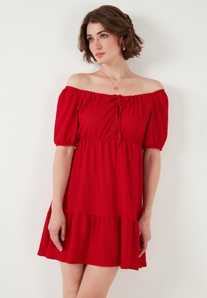 Red, off-the-shoulder dress with puff sleeves, cinched waist, and tiered hem. Textured fabric with a relaxed fit and drawstring detail.