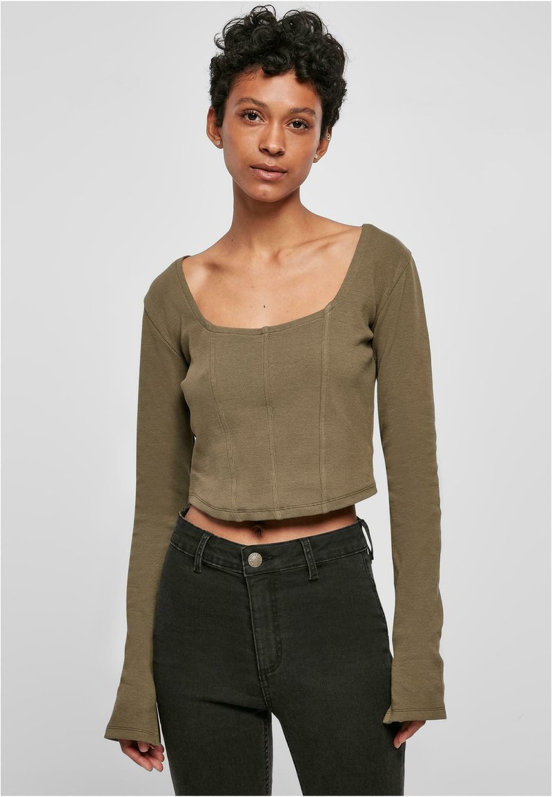 Olivgrünes, cropped Longsleeve-Top mit quadratischem Ausschnitt, das über Nahtdetails und eine figurbetonte Passform verfügt. Getragen mit dunklen Jeans.