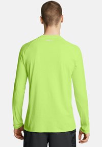 Langarmshirt in Neon-Grün, aus leichtem Material gefertigt. Verfügt über einen runden Halsausschnitt und eine glatte Textur mit Raglanärmeln.