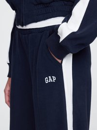 Navy jogger with white side stripes, soft fabric, elastic waistband, and embroidered "GAP" logo on the left pocket area.