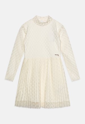 Langärmliges cremefarbenes Spitzenkleid mit hohem Ausschnitt, tailliertem Bund und ausgestelltem Rock mit durchgehendem Rautenmuster im Stoff.