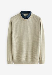 Pull en maille beige texturé superposé sur une chemise bleu marine à col avec encolure boutonnée, présenté à plat sur fond blanc.