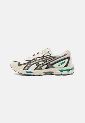 Zapatilla de running blanca y gris con detalles en turquesa, parte superior de malla y logo de la marca en el lateral y la lengüeta, mostrada desde el lado exterior.