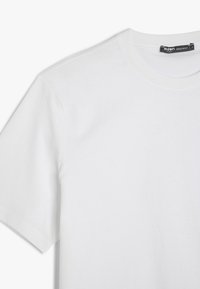 Hvid bomulds t-shirt med normal pasform, rund hals, korte ærmer og glat tekstur. Etiketten på halsudskæringen angiver størrelse og mærke.