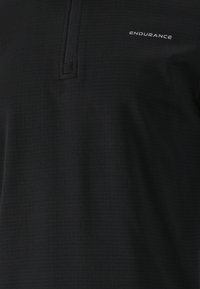 Svart kortärmad topp med fyrdelad dragkedja, med texturerad tyg och "ENDURANCE"-logotyp i vitt på övre vänstra sidan.