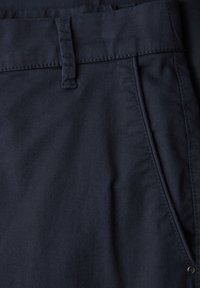Close-up of dark navy blue pants showing waistband, belt loop, side pocket, and visible stitching details.