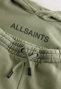 Zielona bluza z kapturem, wyposażona w sznurek i elastyczny pas. Na przodzie nadruk "ALLSAINTS" w ciemnozielonym kolorze. Miękka w dotyku tkanina.