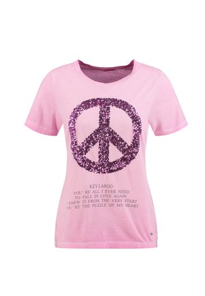 Chemise rose à manches courtes avec un grand symbole de paix en paillettes violettes et un texte sur l'amour et Key Largo imprimé sous le symbole.