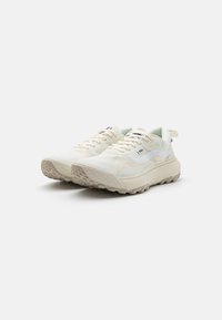 Cream-colored athletic shoes with a textured white overlay and beige rubber outsole. Features include laces, branding on the side, and a pull tab.